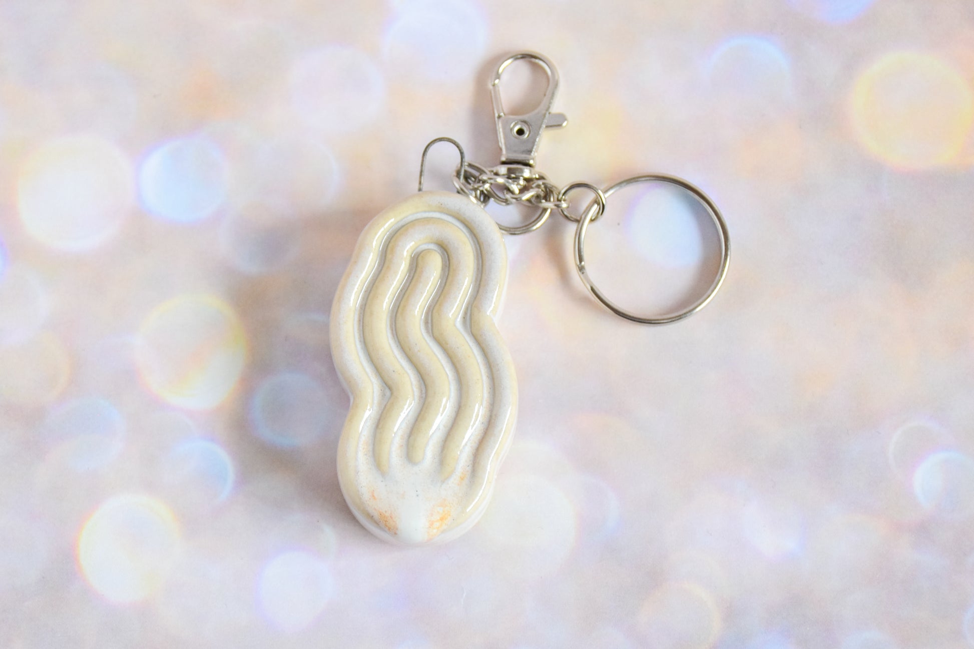 Handmade ceramic accessory titled 'Squigglet Fidget Charm Keychain - Cream' – modern Judaica by Feldi Studios