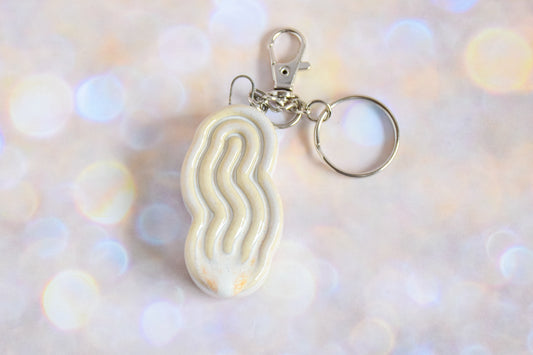 Handmade ceramic accessory titled 'Squigglet Fidget Charm Keychain - Cream' – modern Judaica by Feldi Studios